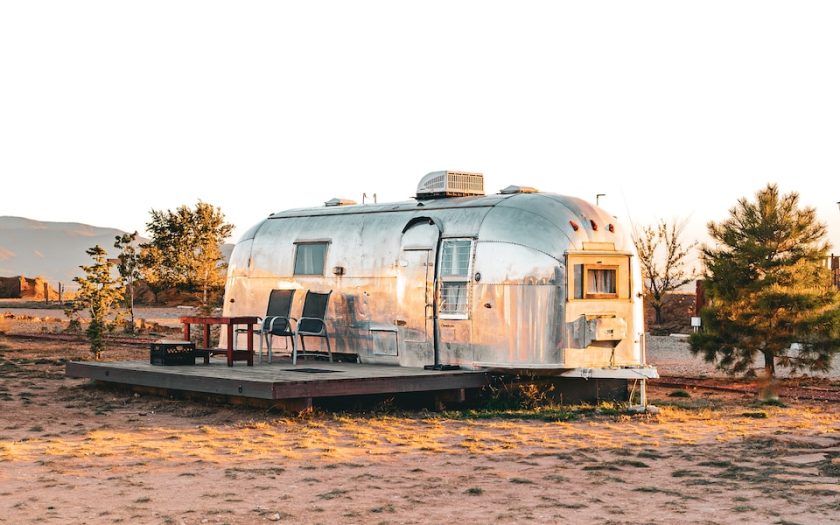 a silver trailer parked in a field next to trees