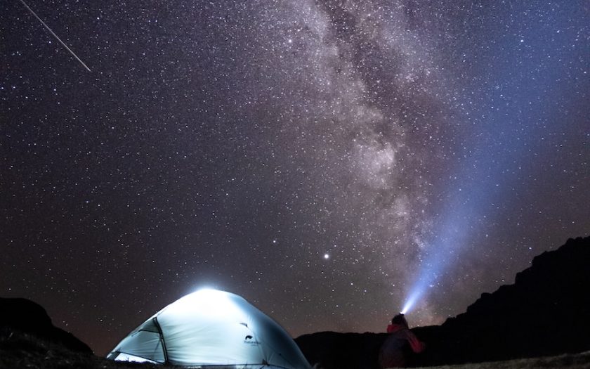 a tent in the middle of a field under a night sky filled with stars