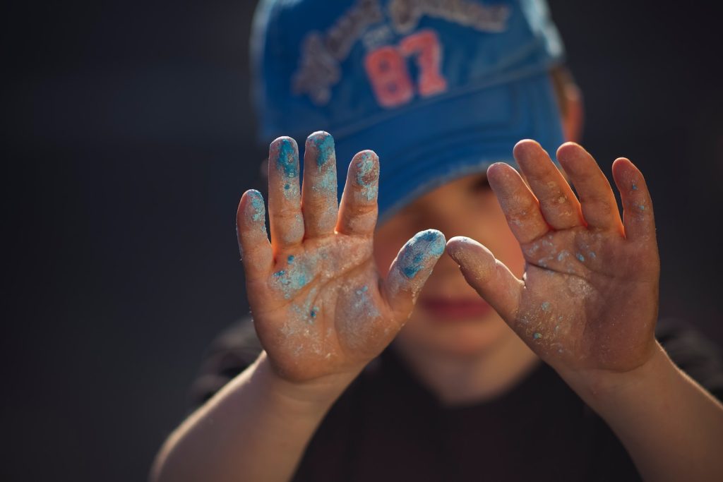 person in blue and white shirt covering face with hands