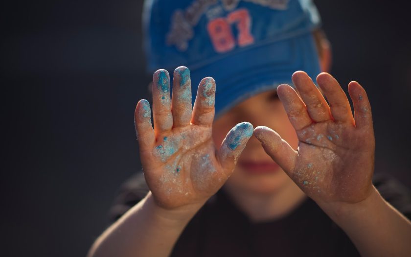 person in blue and white shirt covering face with hands