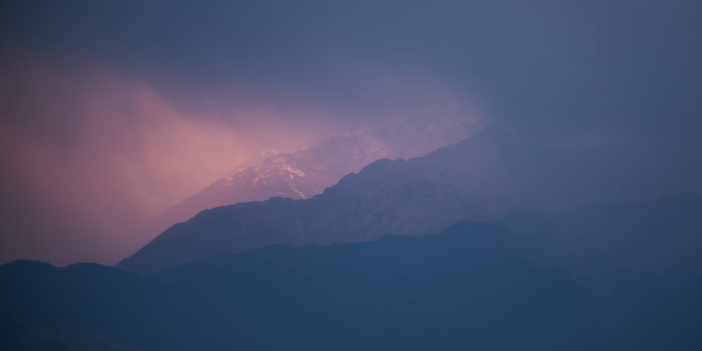 a view of a mountain covered in snow under a cloudy sky