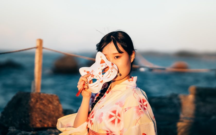 a woman in a kimono is holding a mask