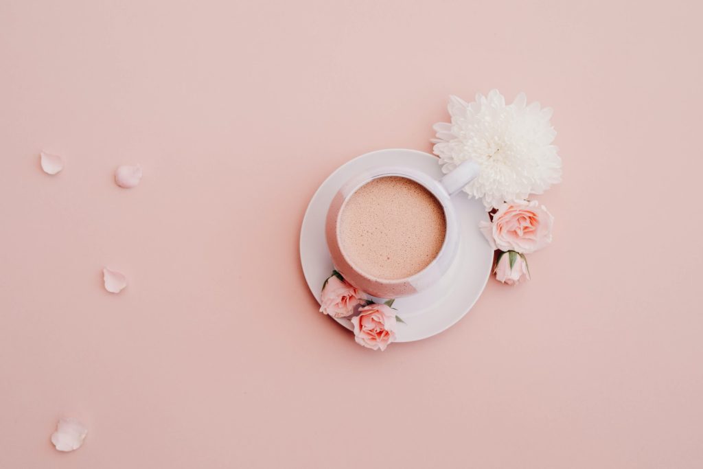 white glazed cup with saucer on pink surface