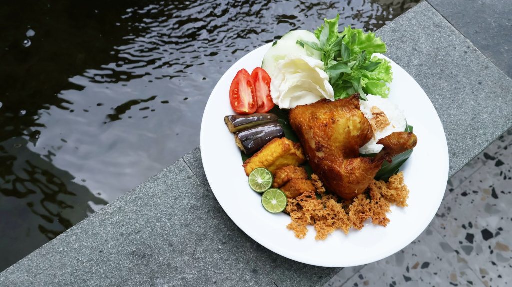 a white plate topped with meat and veggies next to a body of water