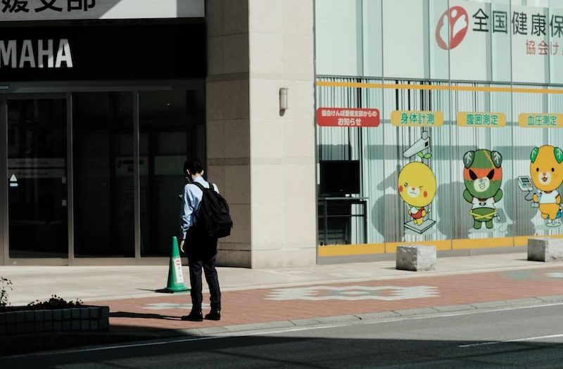 a man standing on the side of a road next to a tall building