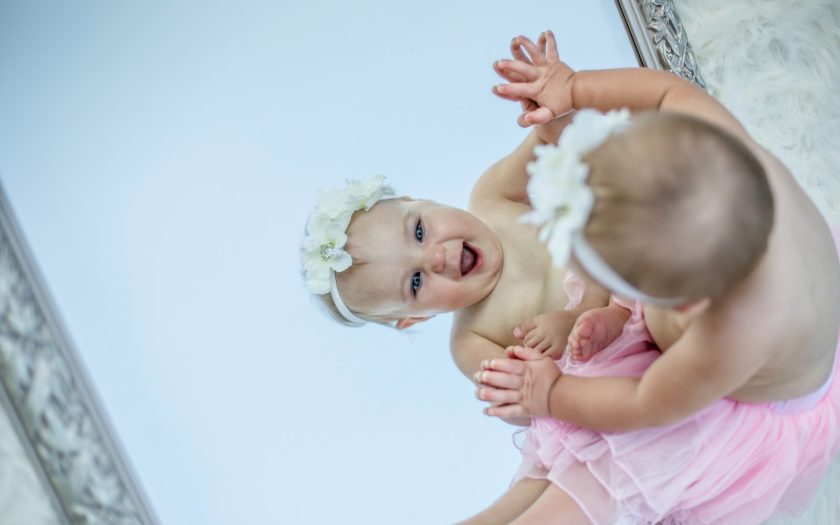 toddler facing mirror while smiling