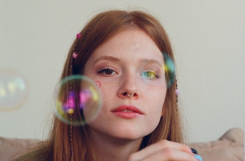 a woman sitting on a couch blowing bubbles